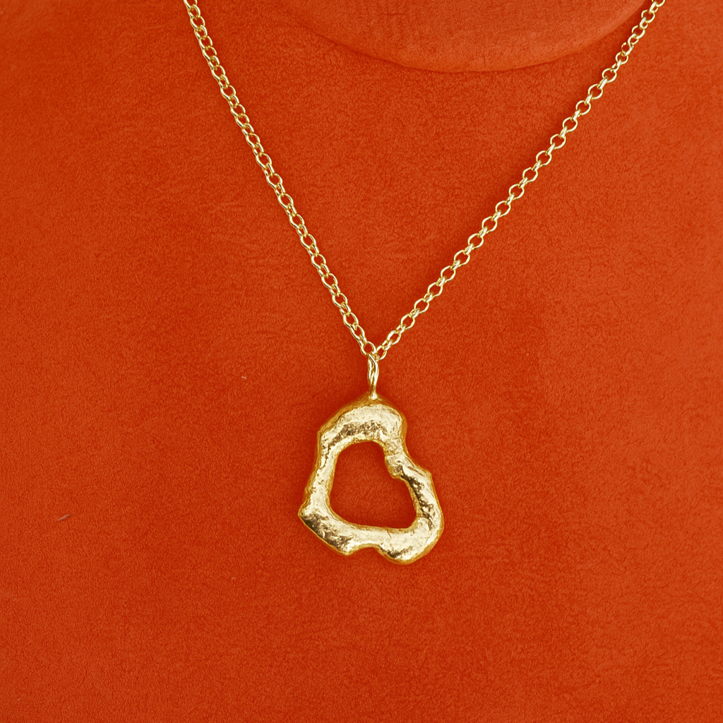 Gold melted shaped pendant necklace on a red background