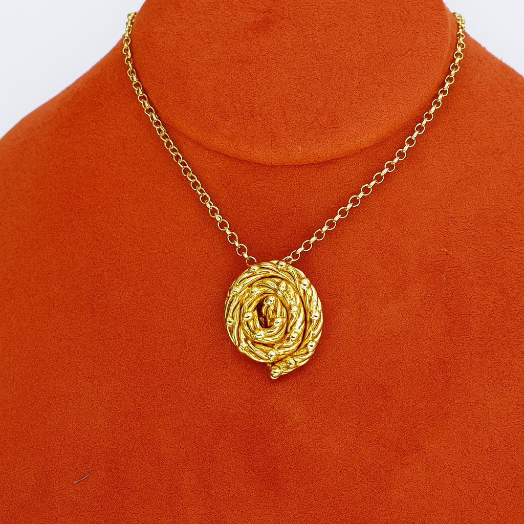 Gold necklace with a rose-shaped pendant on an orange stand.
