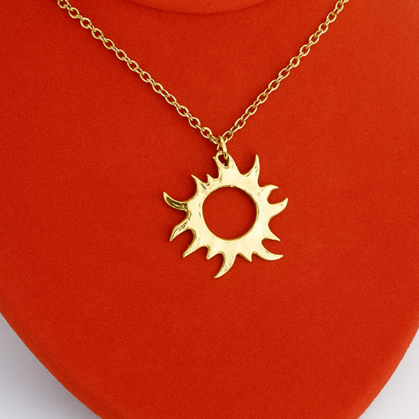 Gold necklace with a sun pendant on an orange stand