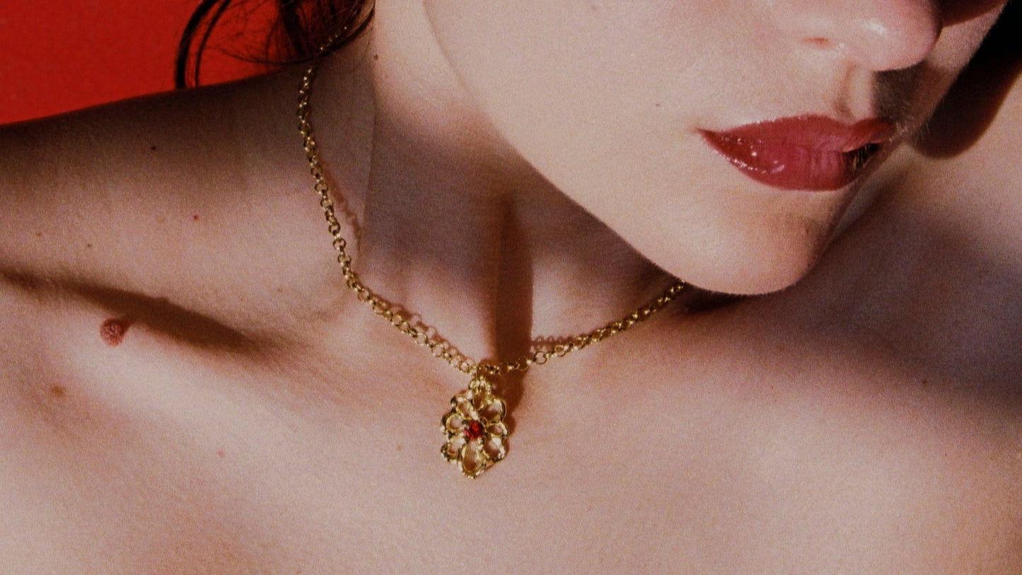 Close-up of a woman wearing gold jewelry against a red background