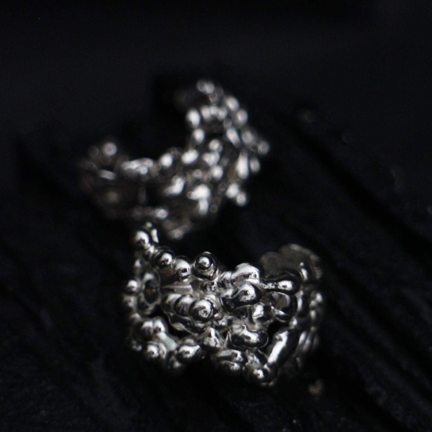 Close-up of a silver ring with intricate design on a dark background