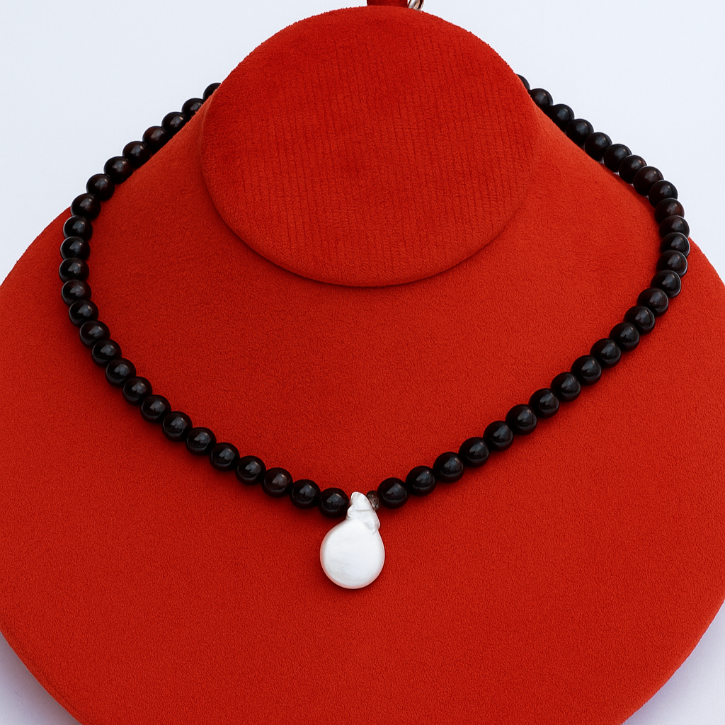 red beaded necklace with a white pendant on a red stand against a light blue background