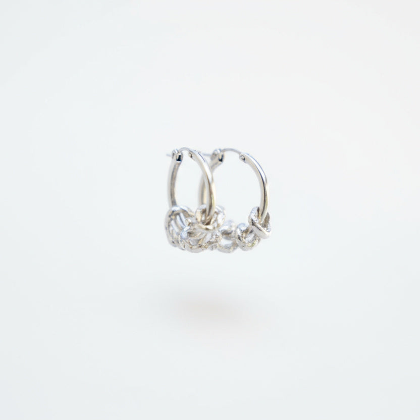 Silver hoop earrings with clear gemstones on a white background