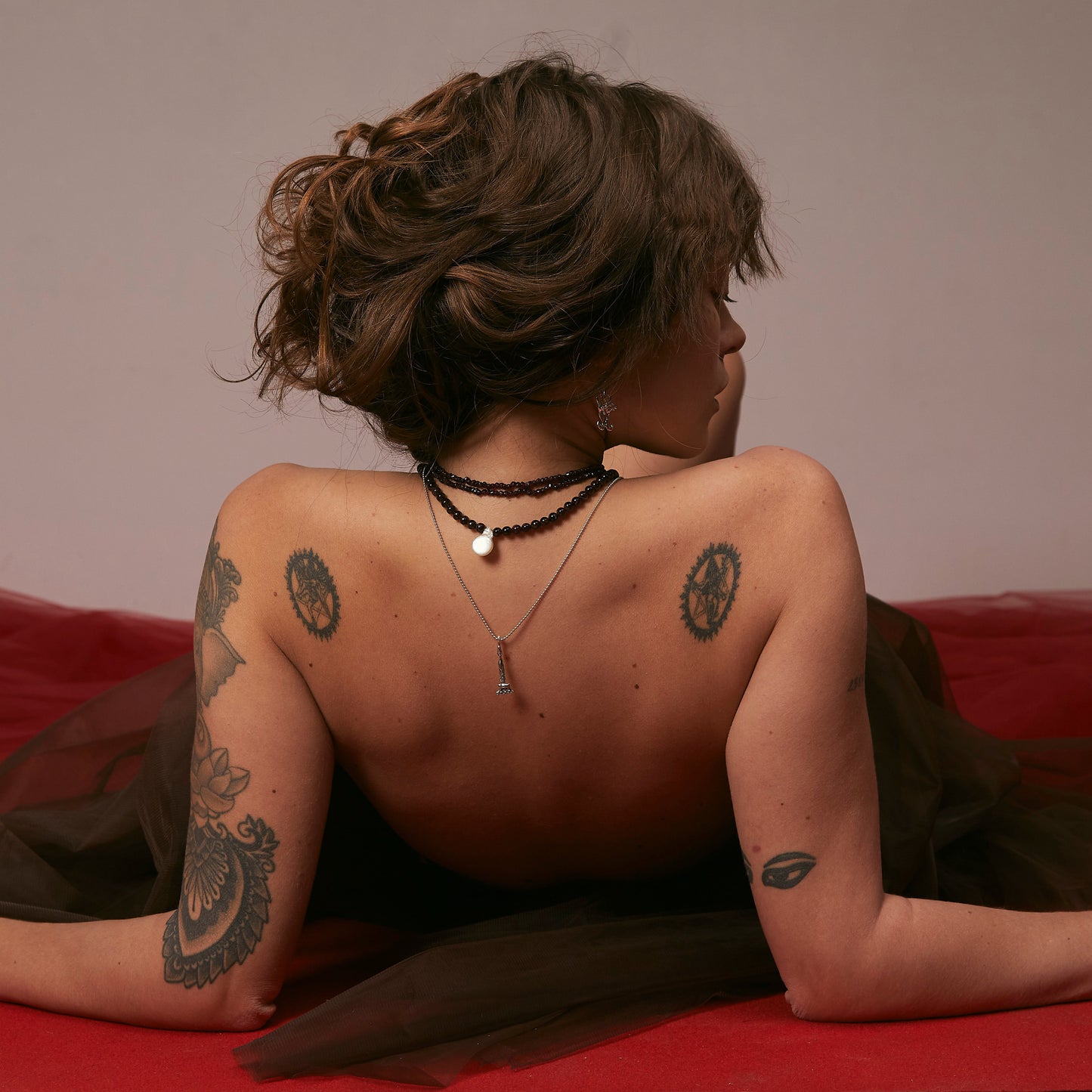 Person with tattoos lying on a red surface