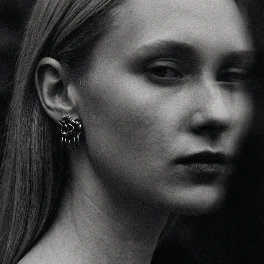 Black and white close-up of a person wearing a unique earring.
