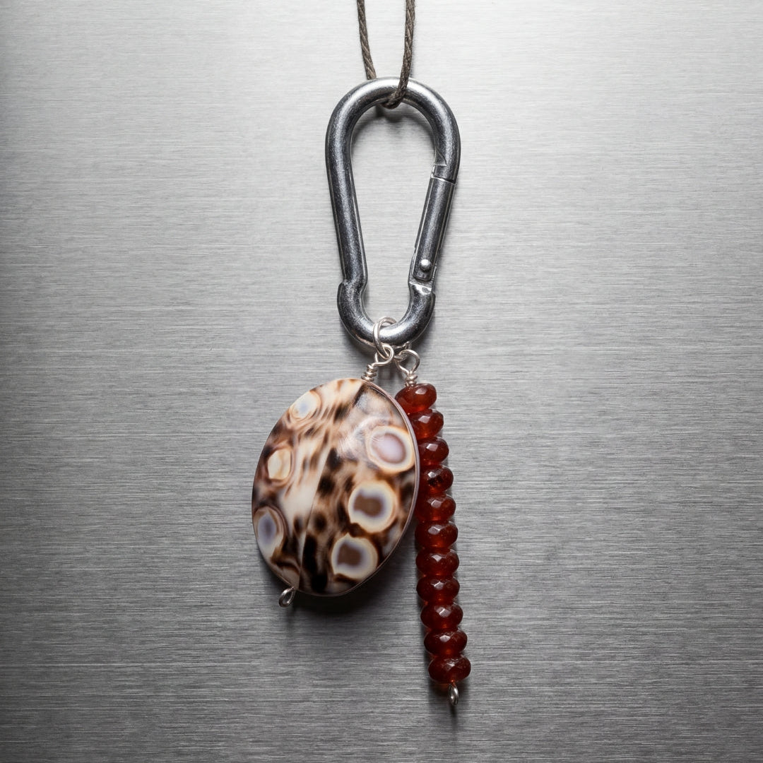 Necklace with a carabiner and two beads on a metallic surface