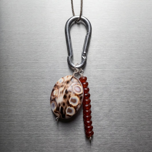 Necklace with a carabiner and two beads on a metallic surface