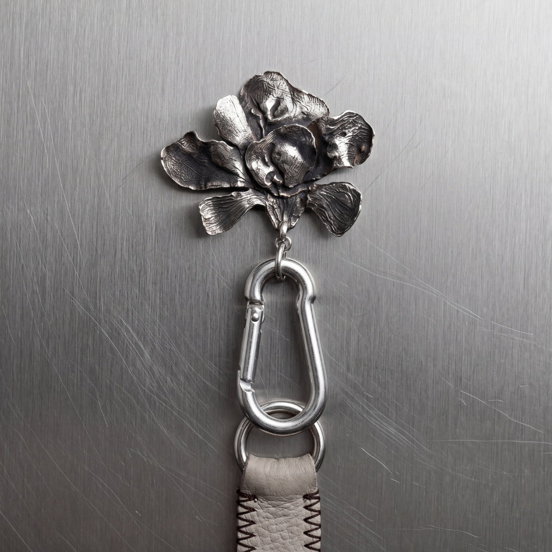 Metallic flower-shaped keychain attached to a metal surface