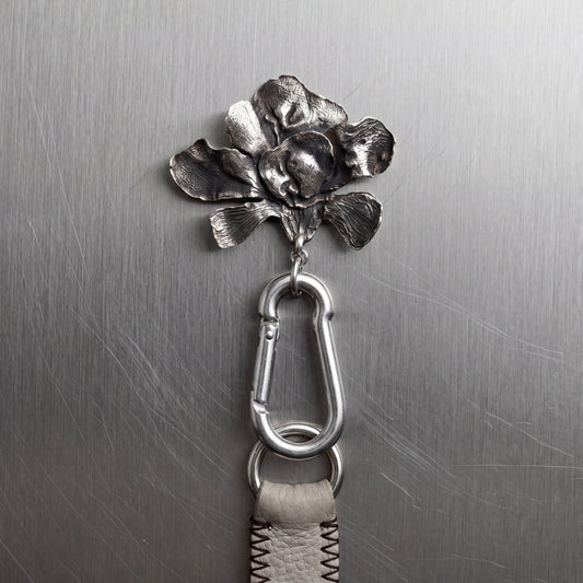 Metallic flower-shaped keychain attached to a metal surface