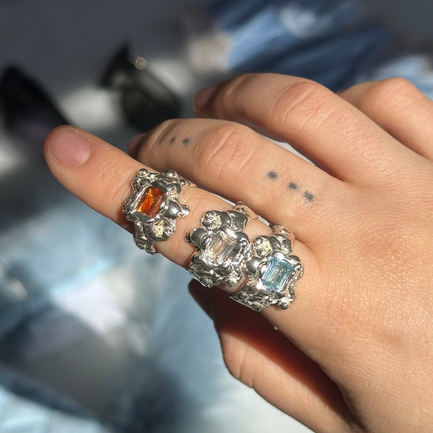 Hand wearing multiple rings with gemstones on a blurred background