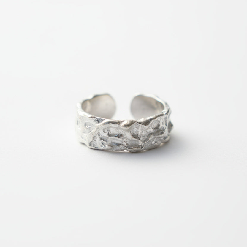 Silver ring with textured design on a white background