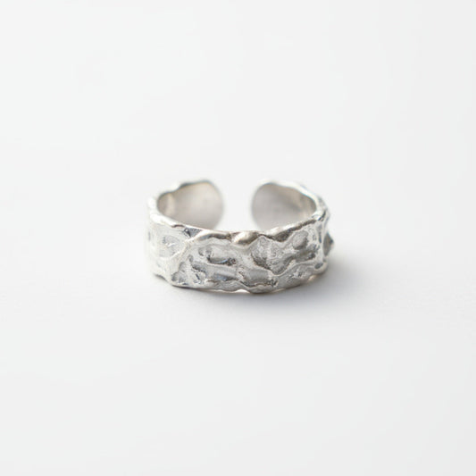 Silver ring with textured design on a white background