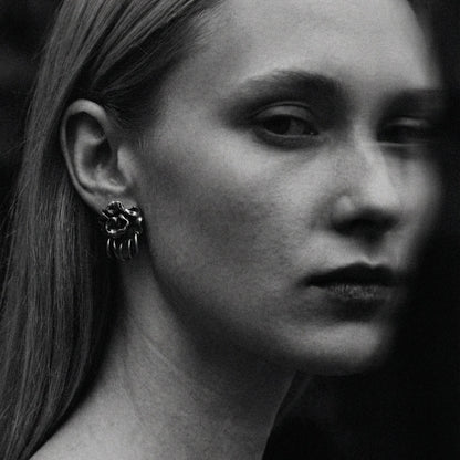 Black and white close-up of a person wearing a unique earring.