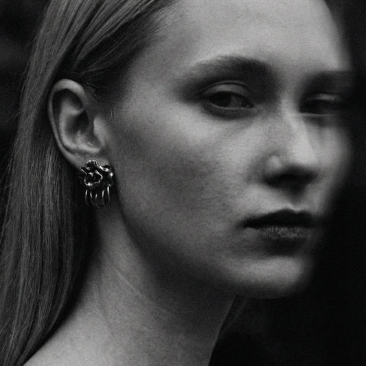 Black and white close-up of a person wearing a unique earring.